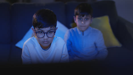 Front-View-Of-Two-Young-Boys-At-Home-Having-Fun-Playing-With-Computer-Games-Console-On-TV-Holding-Controllers-Late-At-Night-1
